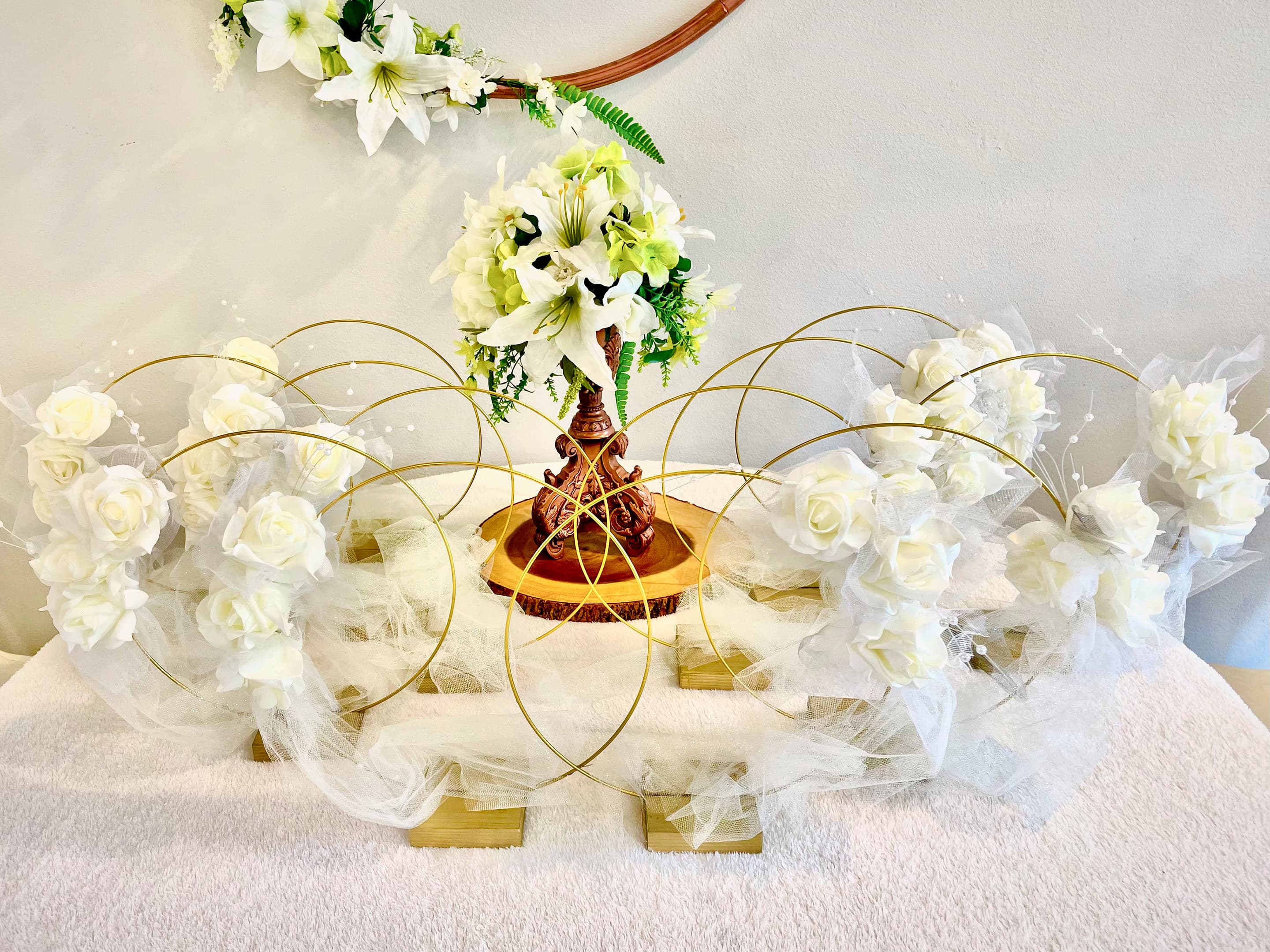 A centrepiece of white roses, lilies and gold wire rings