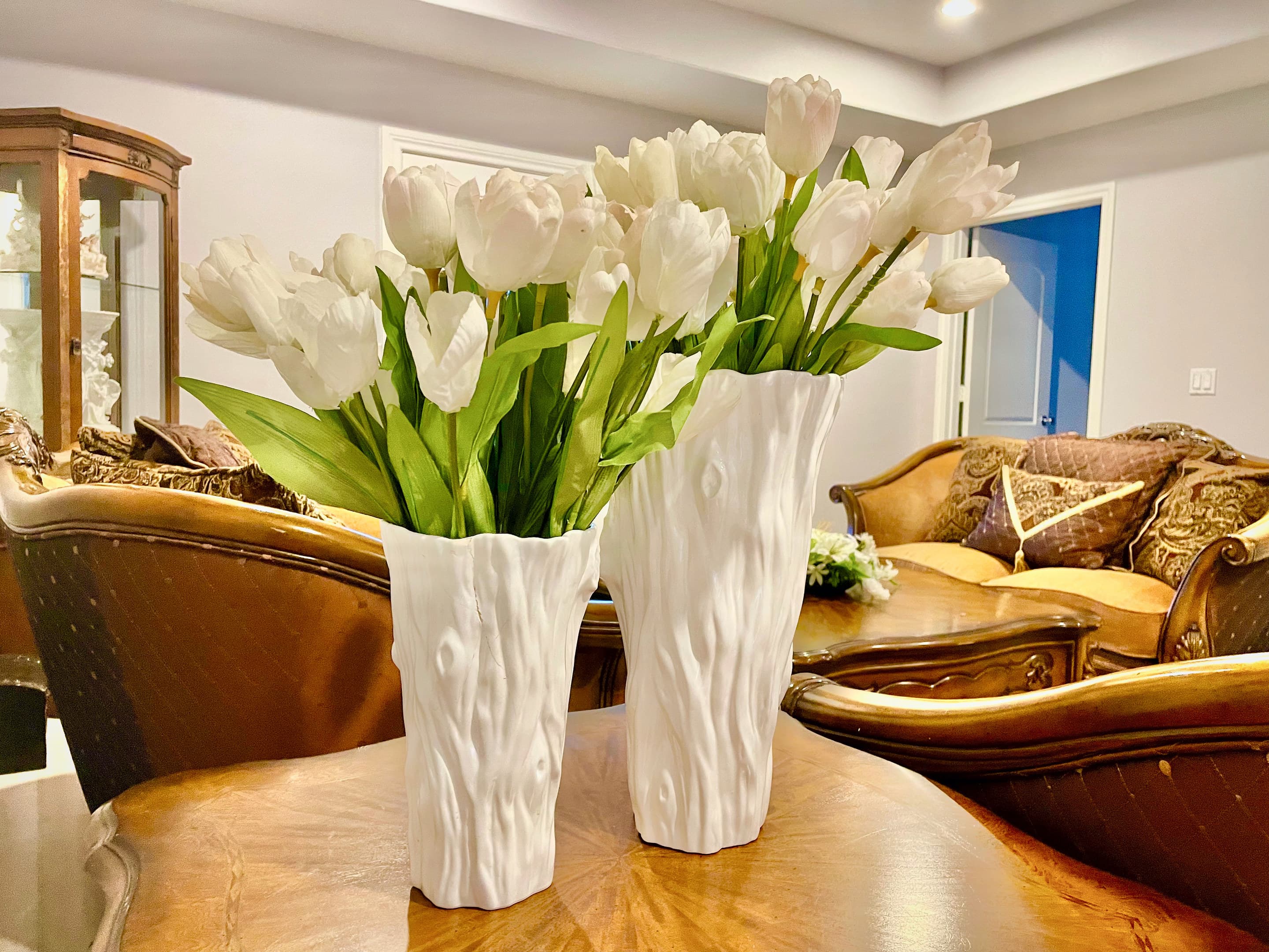 White tulips in sculpted vases on a polished table in the sitting room