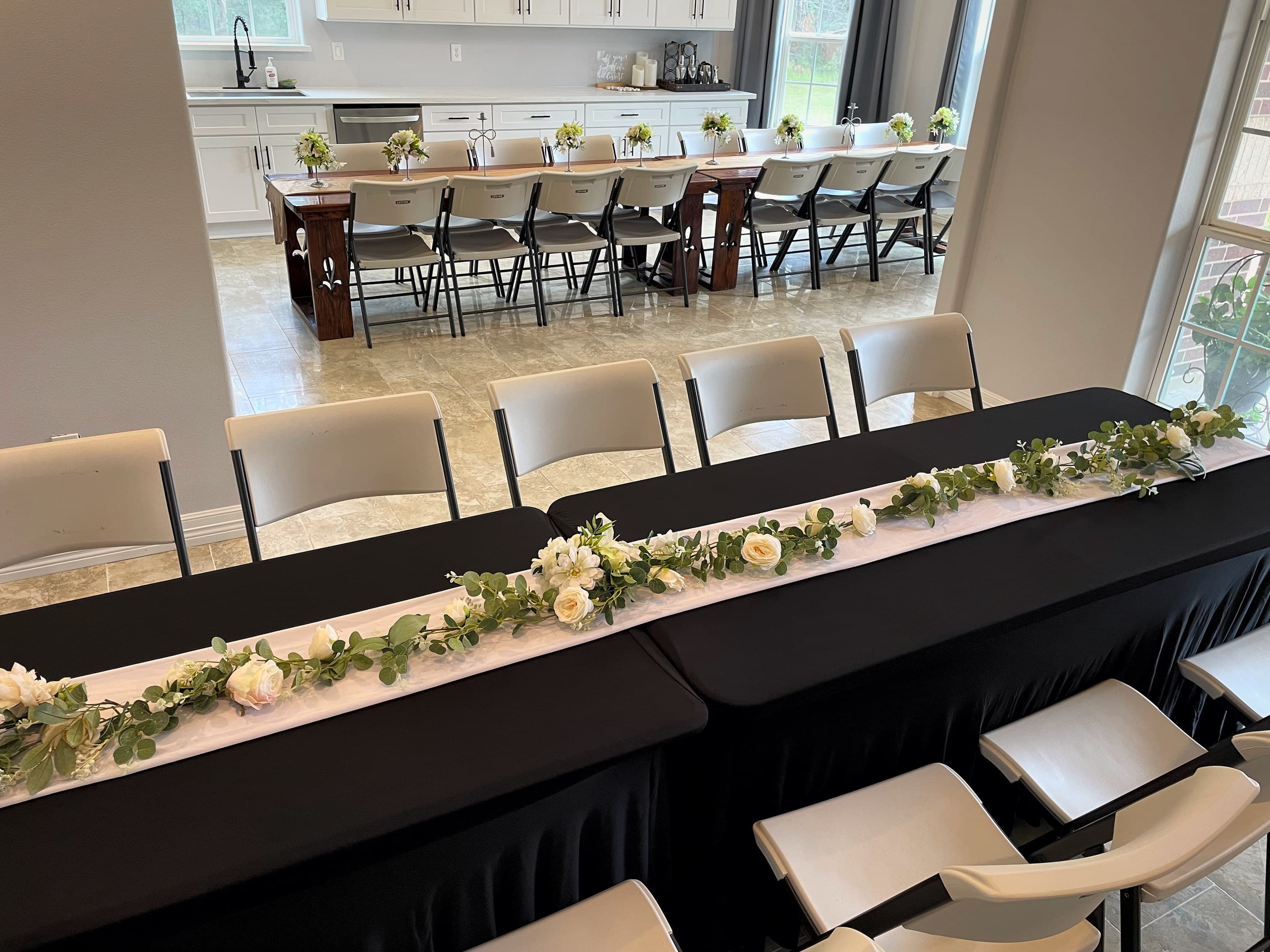 Banquet tables in black linen with garlands of greenery and white roses
