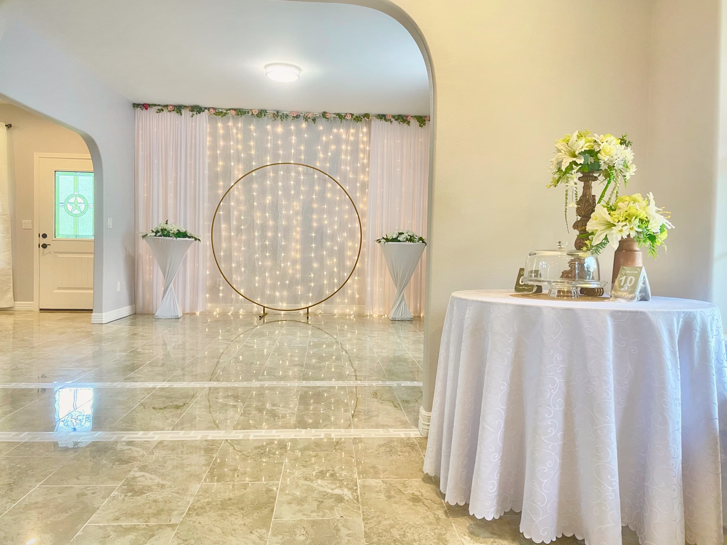 A round table of lilies before an illuminated ceremony backdrop on polished marble floors
