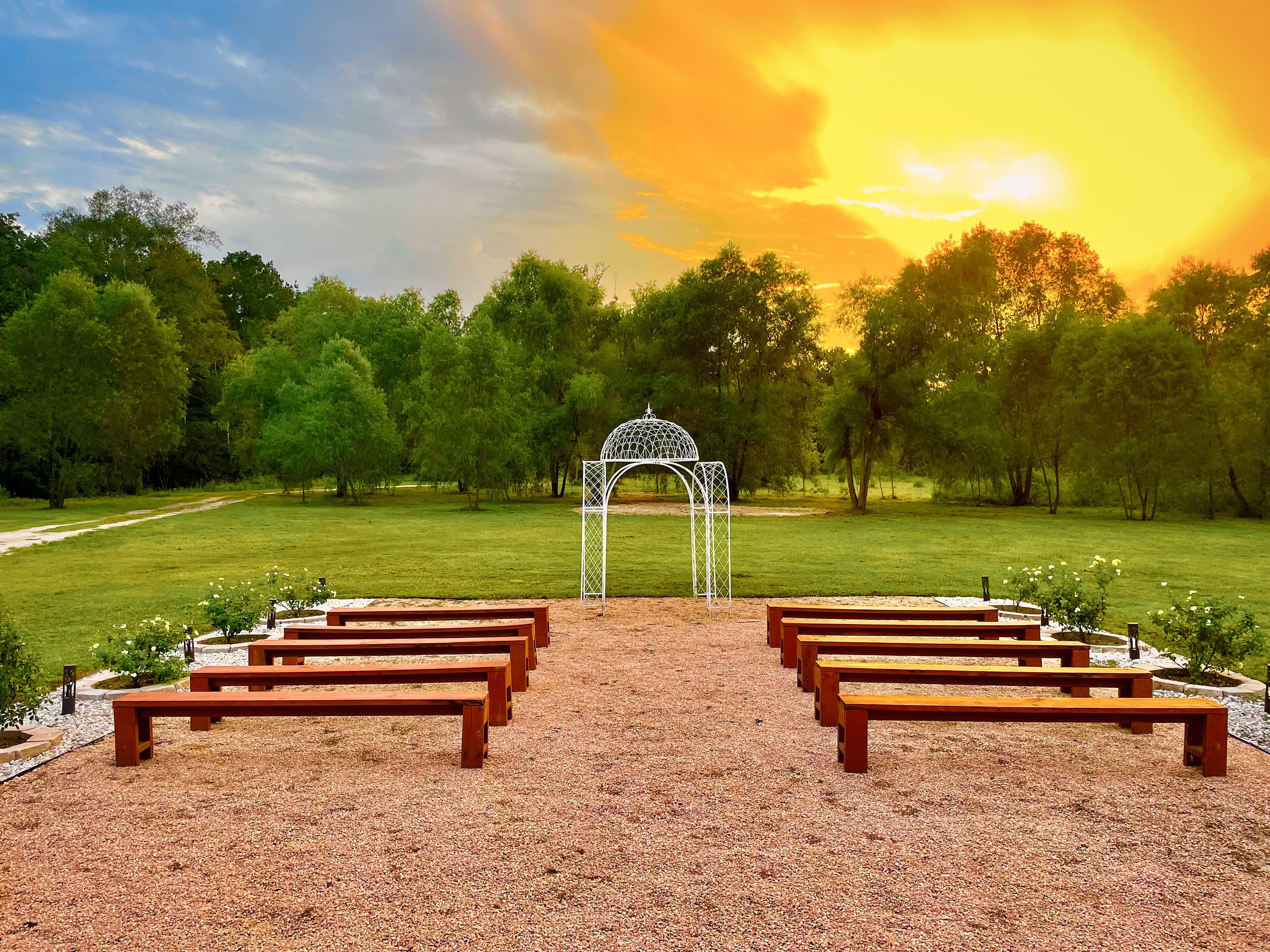 Timber benches facing the white gazebo beneath a glowing evening sky
