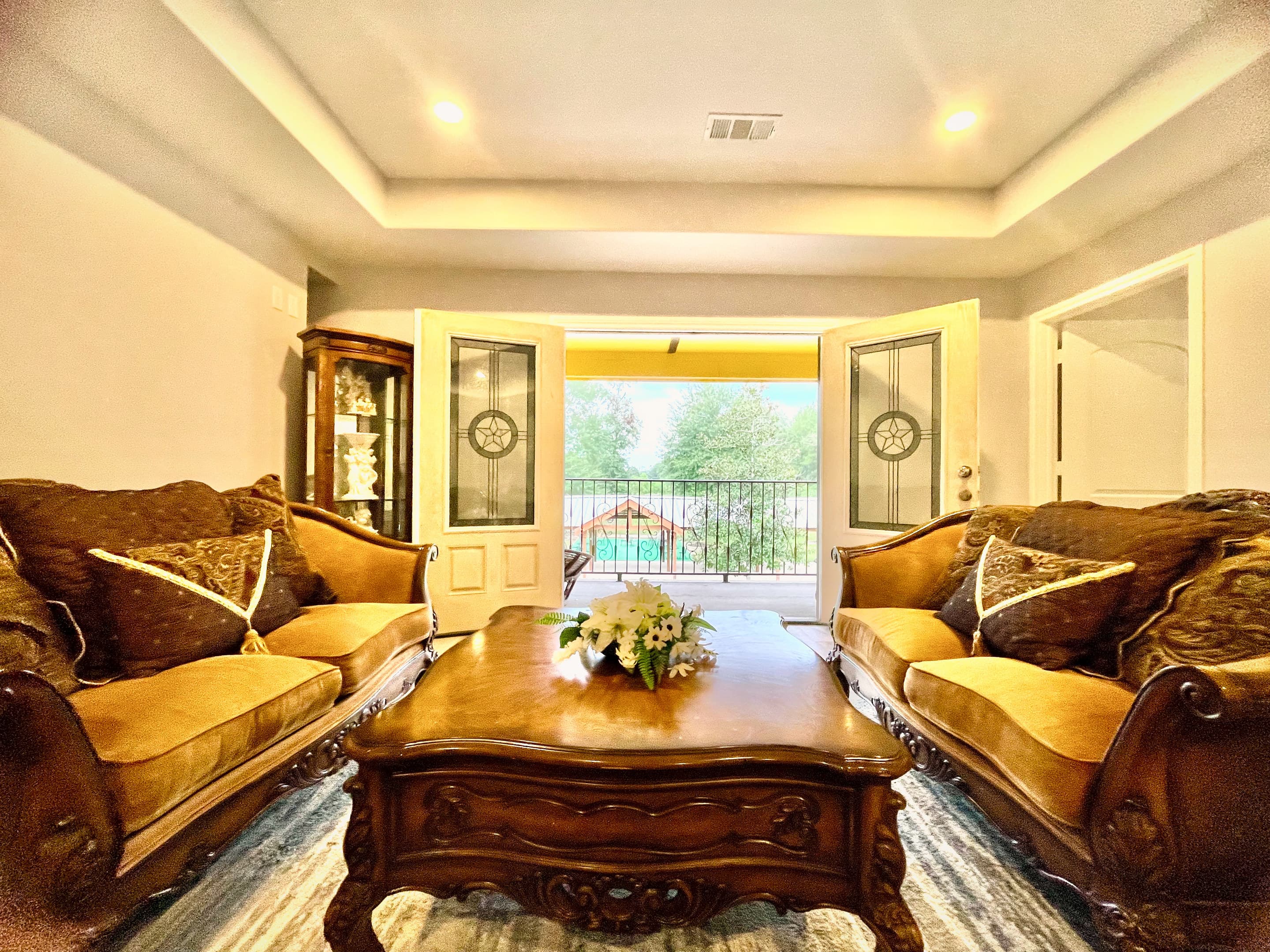 A formal sitting room with carved furniture and French doors open to the terrace