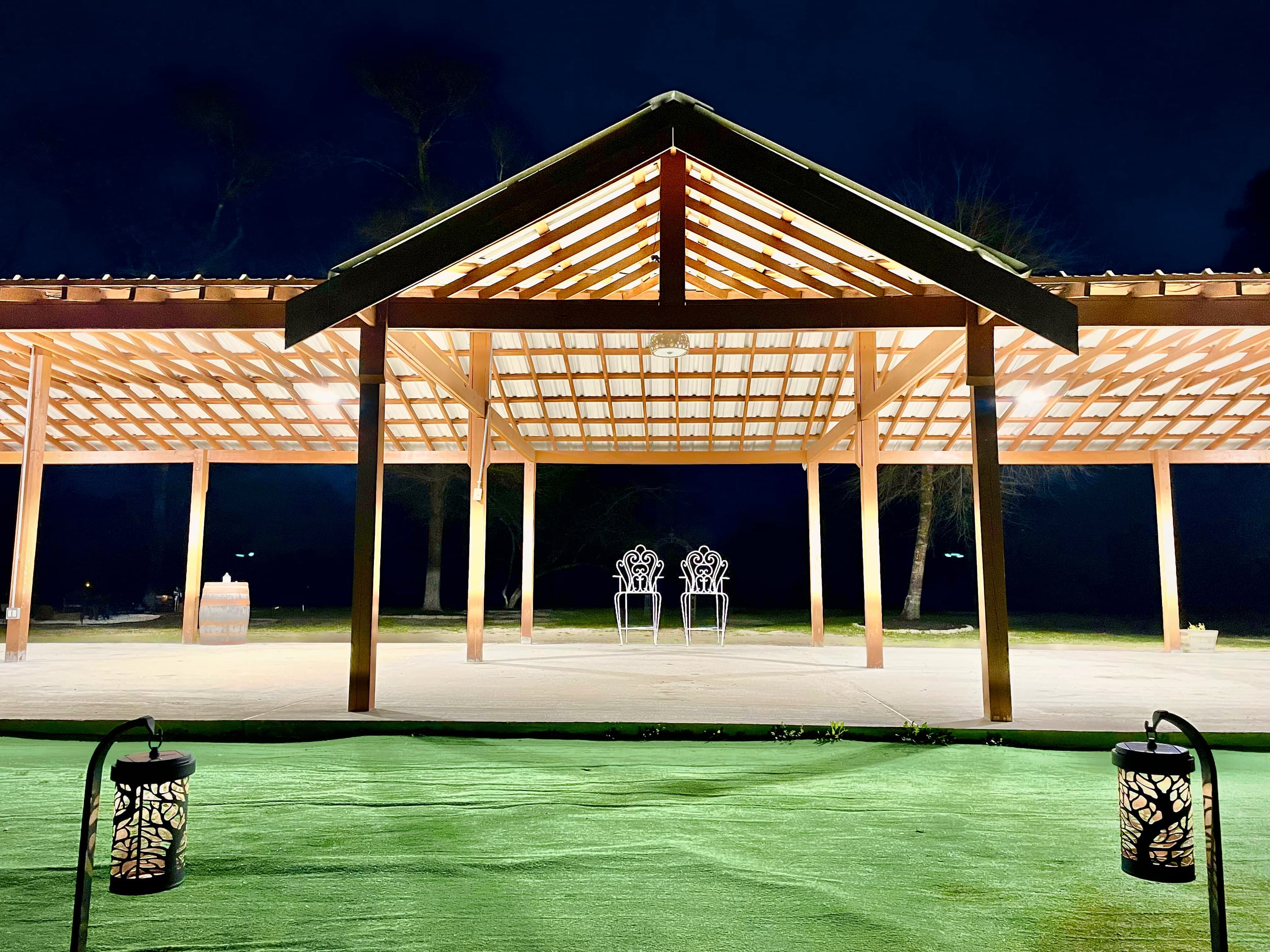 The pavilion's timber roof lit from within against the night sky