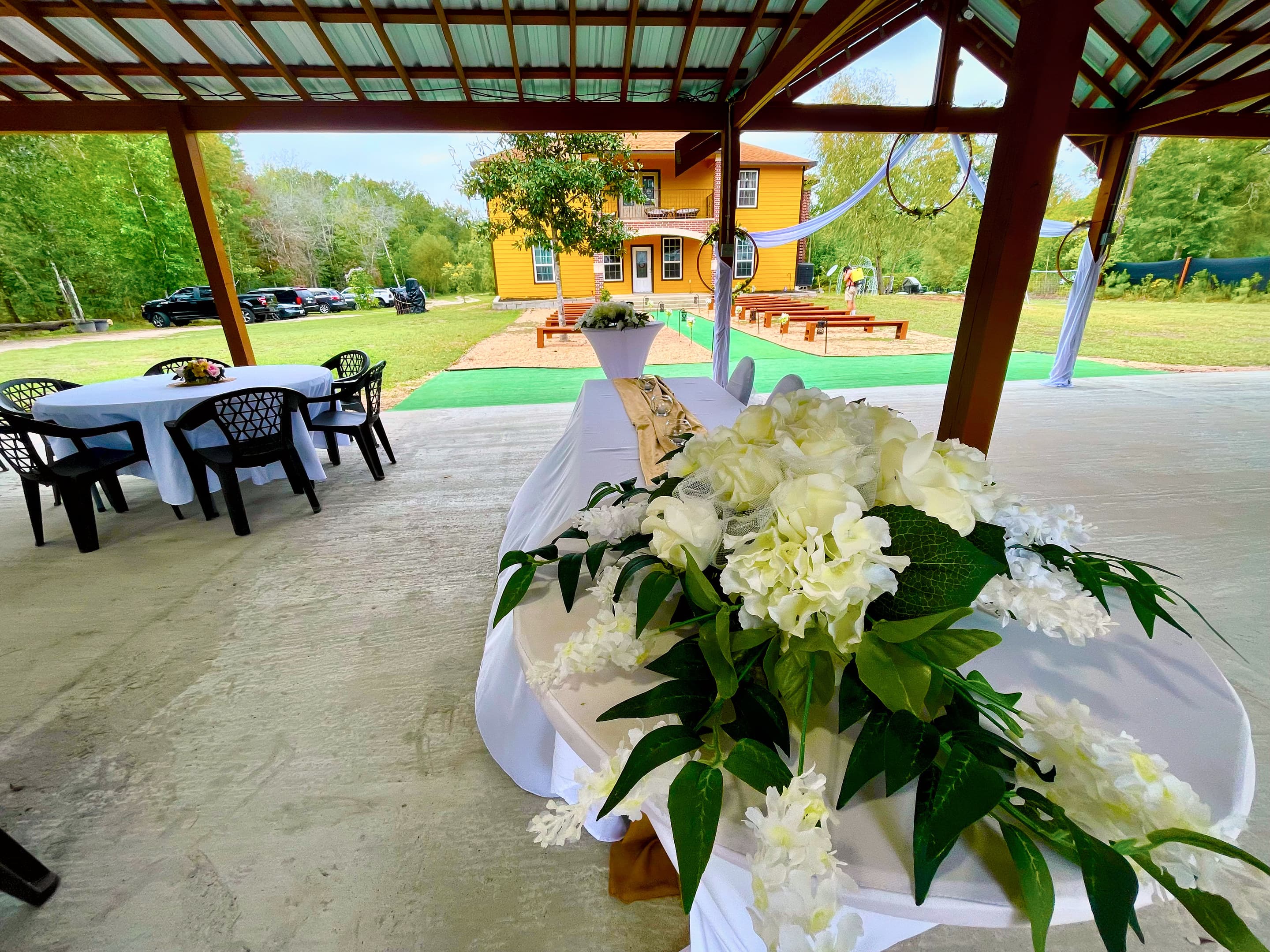 A white floral arrangement on a linen-dressed table beneath the pavilion