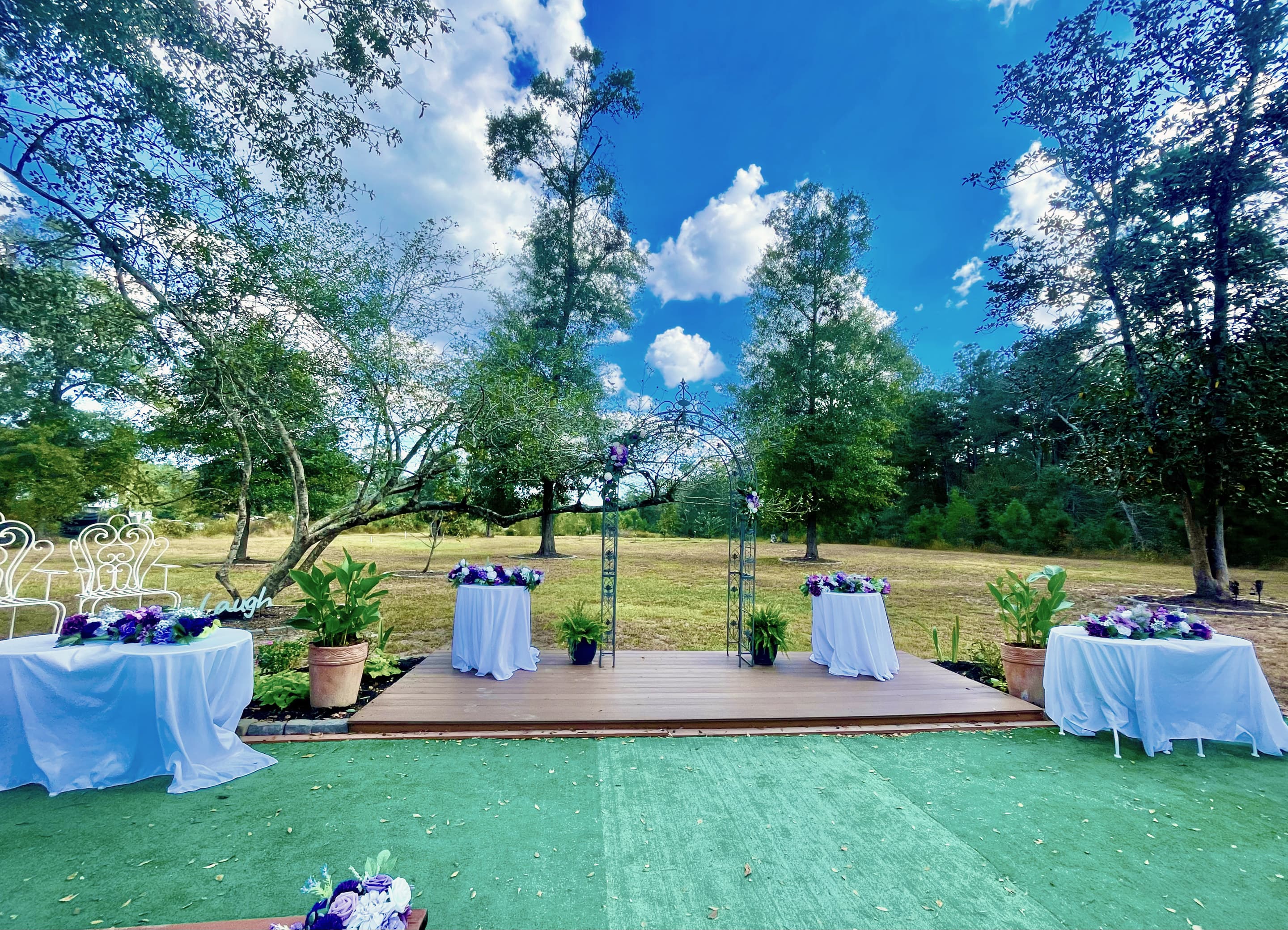 Cocktail tables in white linen around the stage on the turf patio