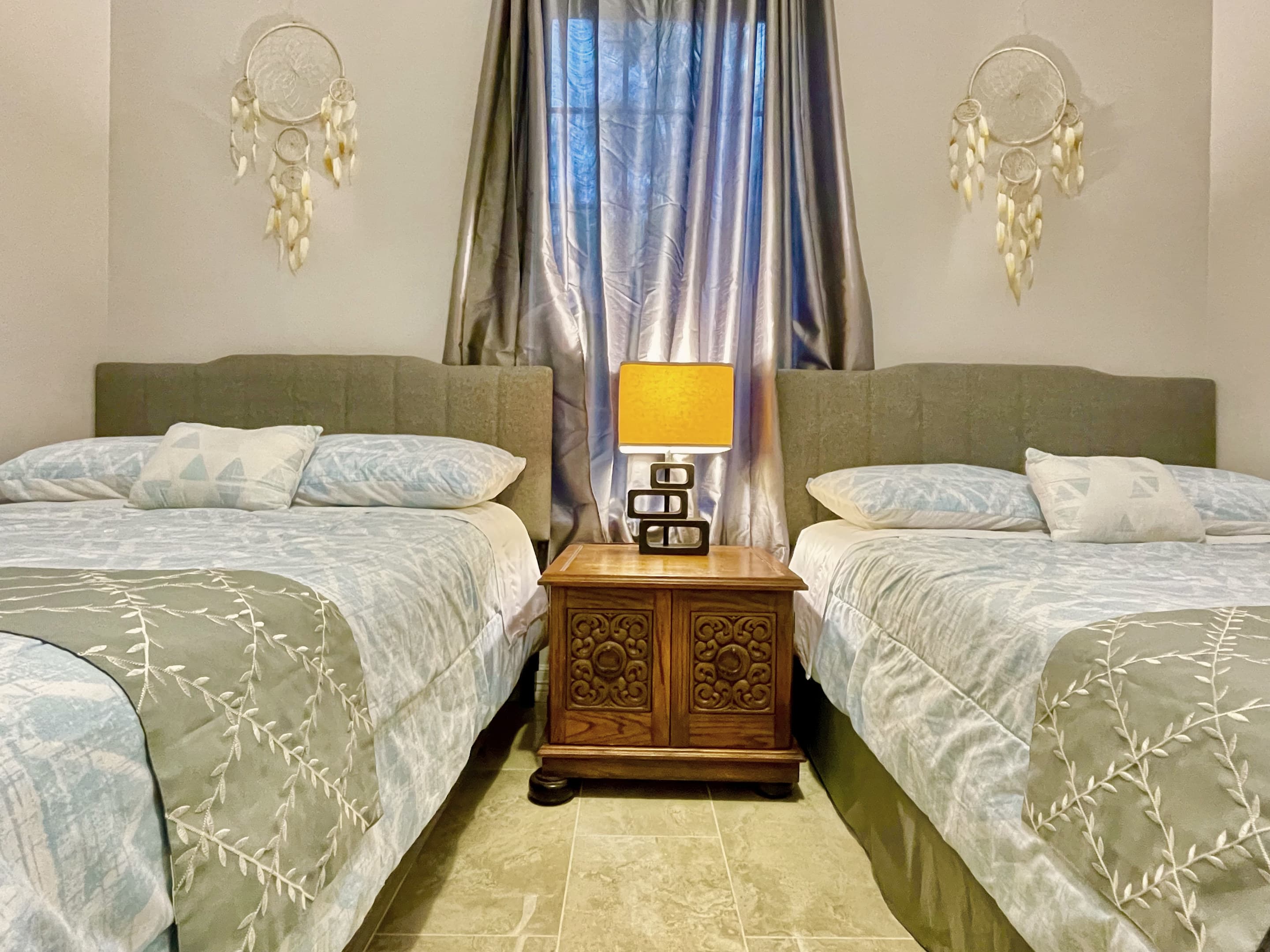 A bedroom with two beds in soft grey linens