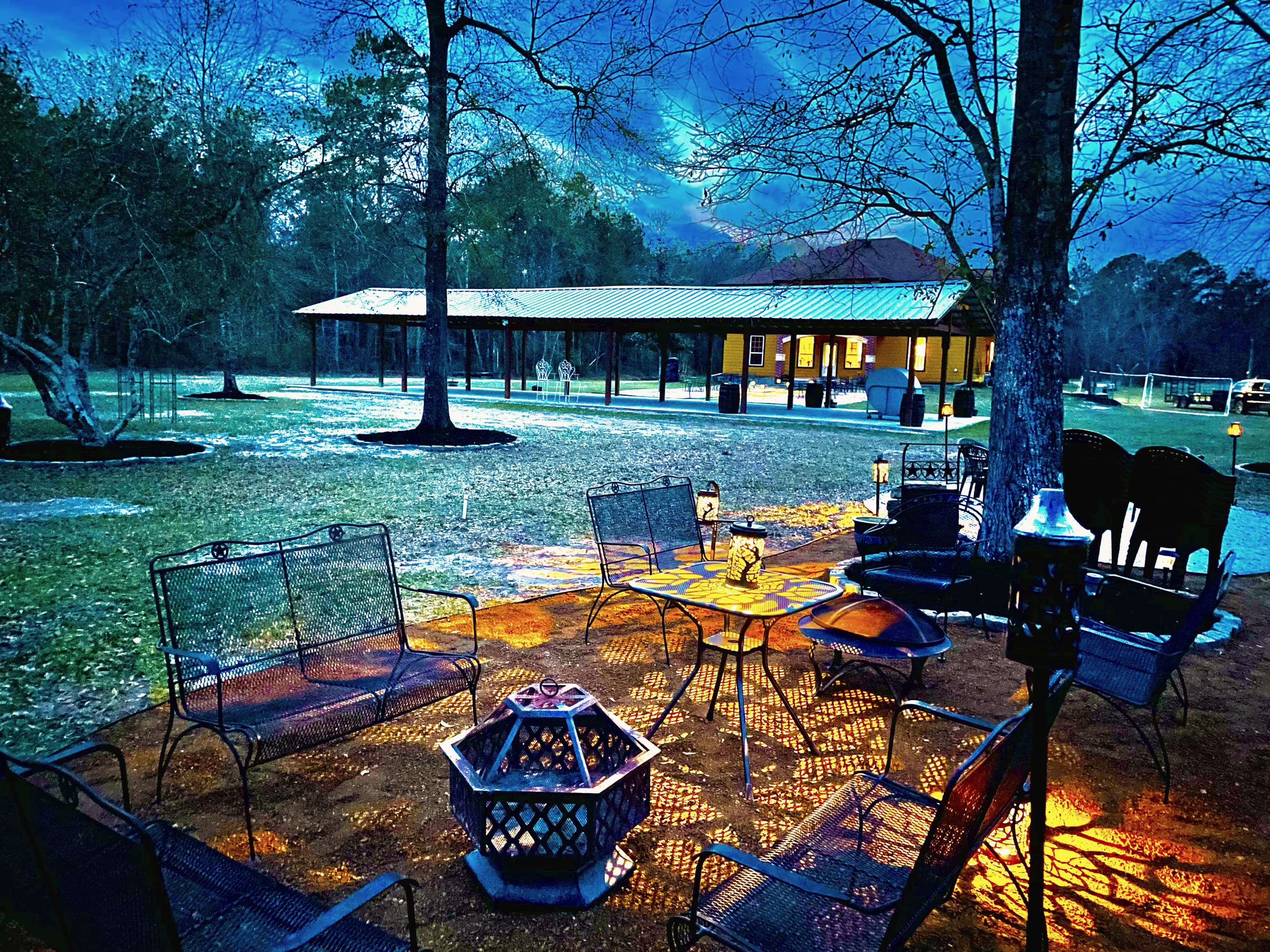 The fire pit area at dusk, lanterns glowing and the pavilion lit behind