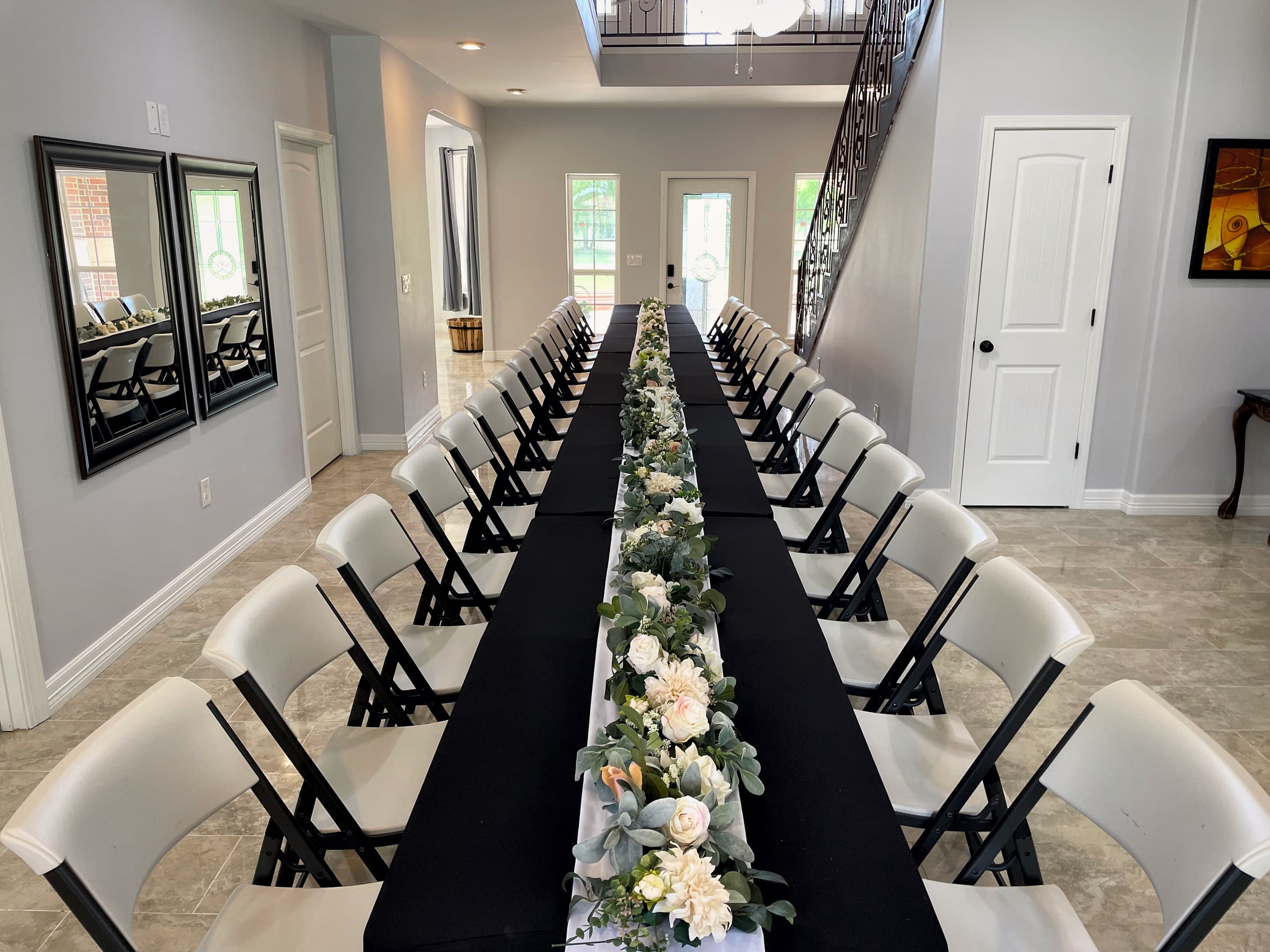 A long banquet table in the manor hall, its runner of white roses and eucalyptus leading to the staircase
