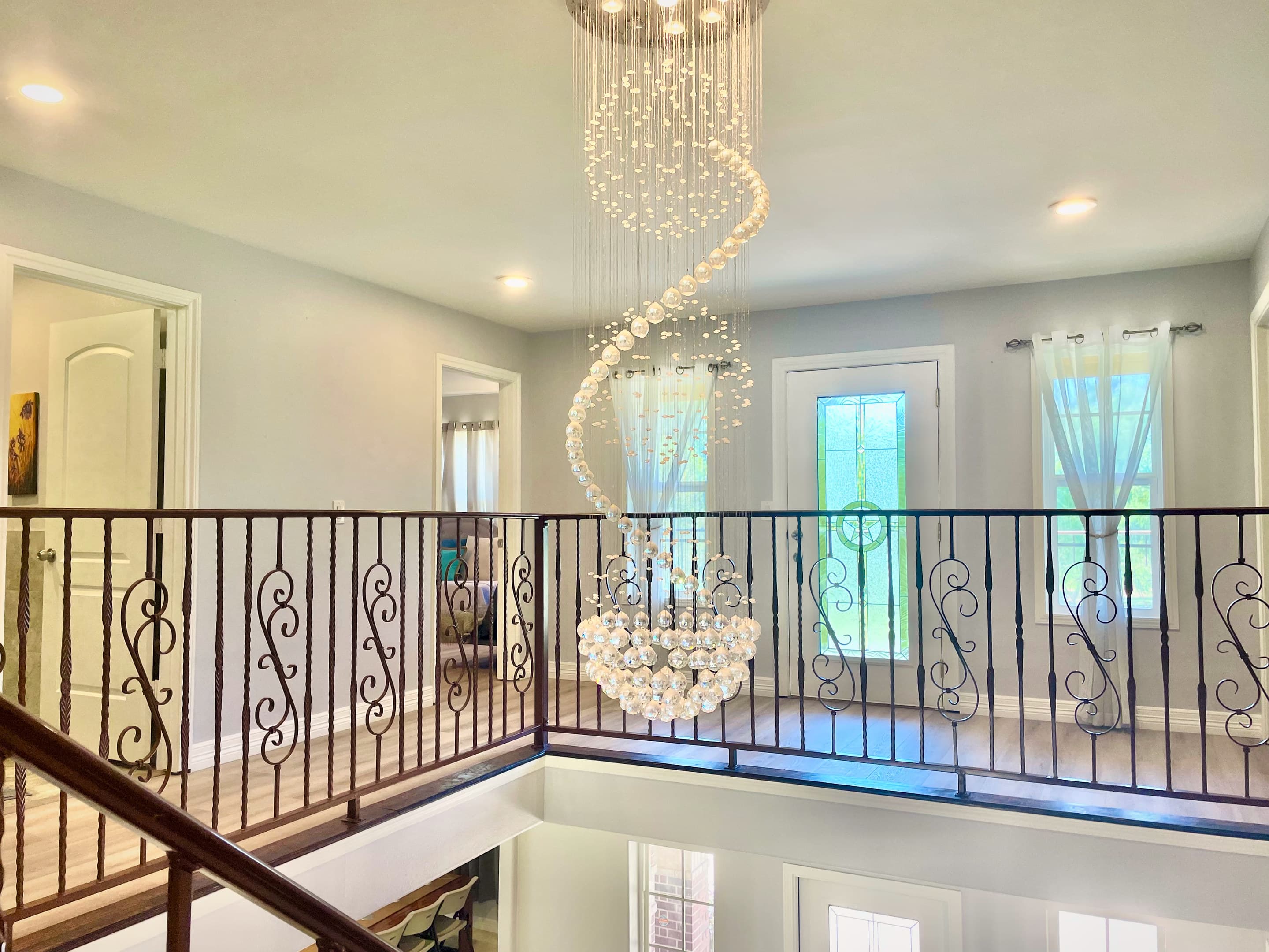 A spiral crystal chandelier descending through the manor's double-height stairwell