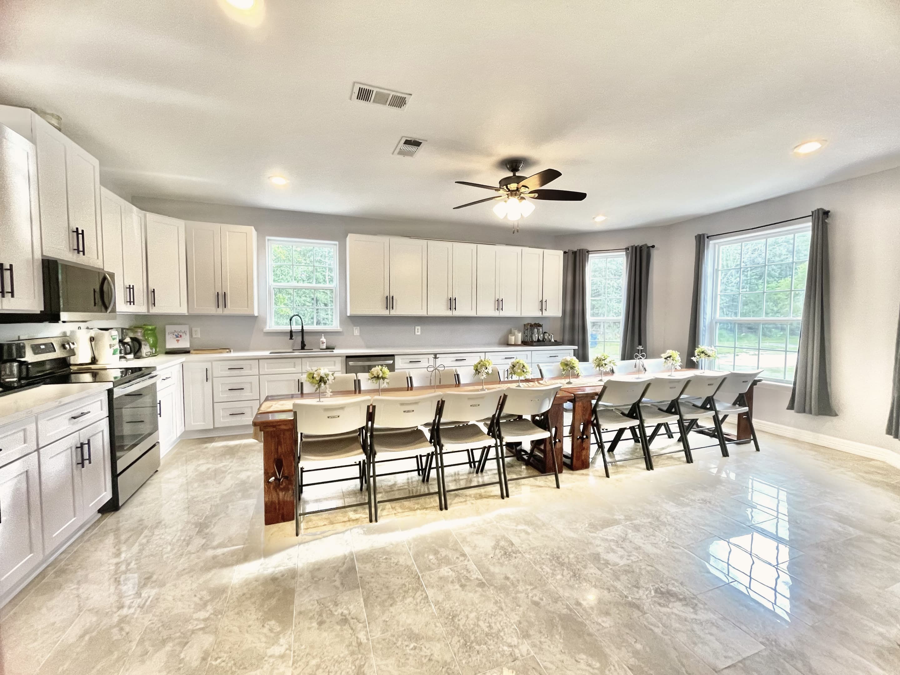 The full-size kitchen with a long breakfast bar, white cabinets and a large dining table