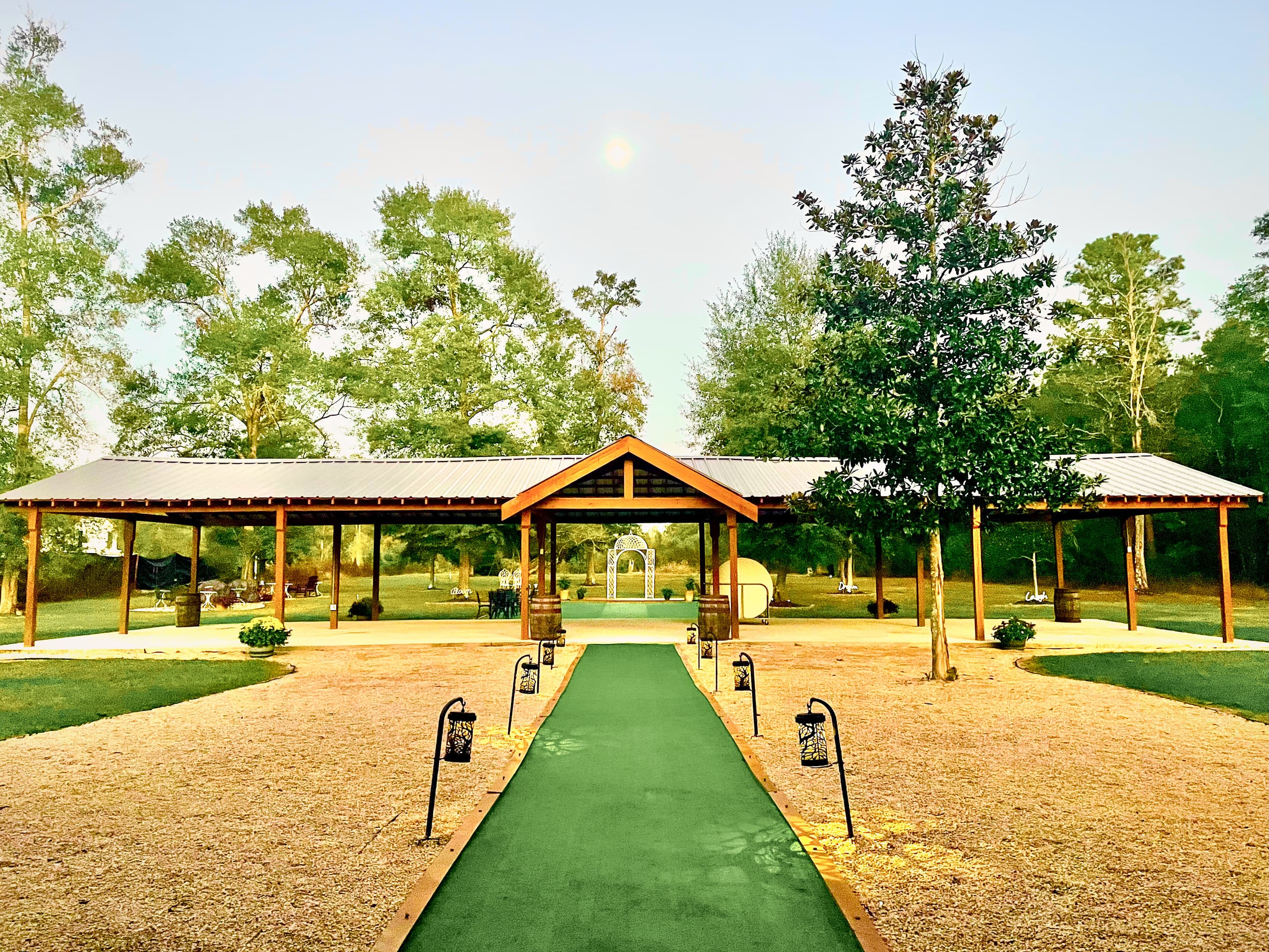 A lantern-lined aisle leading to the long timber pavilion at twilight