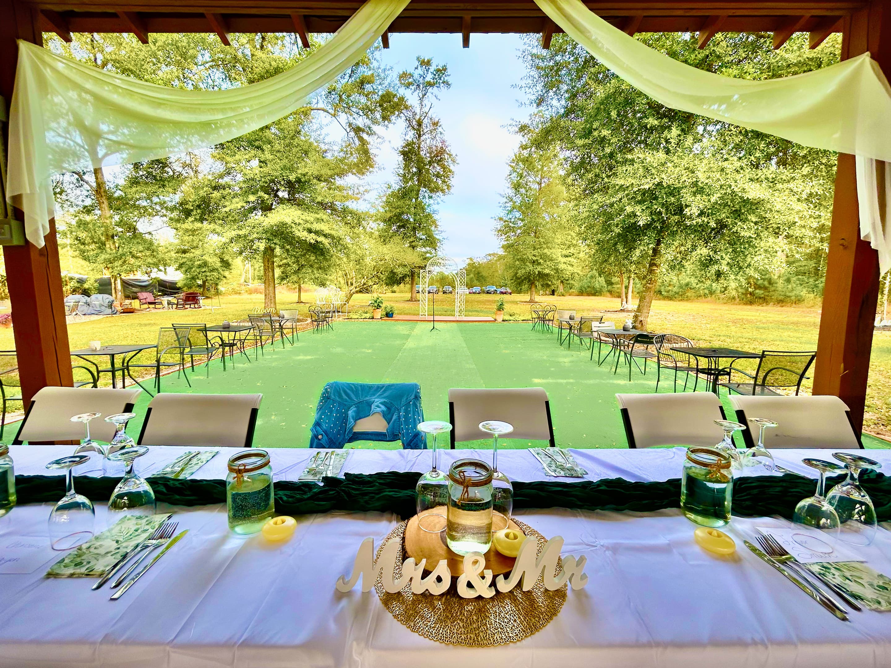 A head table set with glassware and a Mr & Mrs sign, looking out across the lawn
