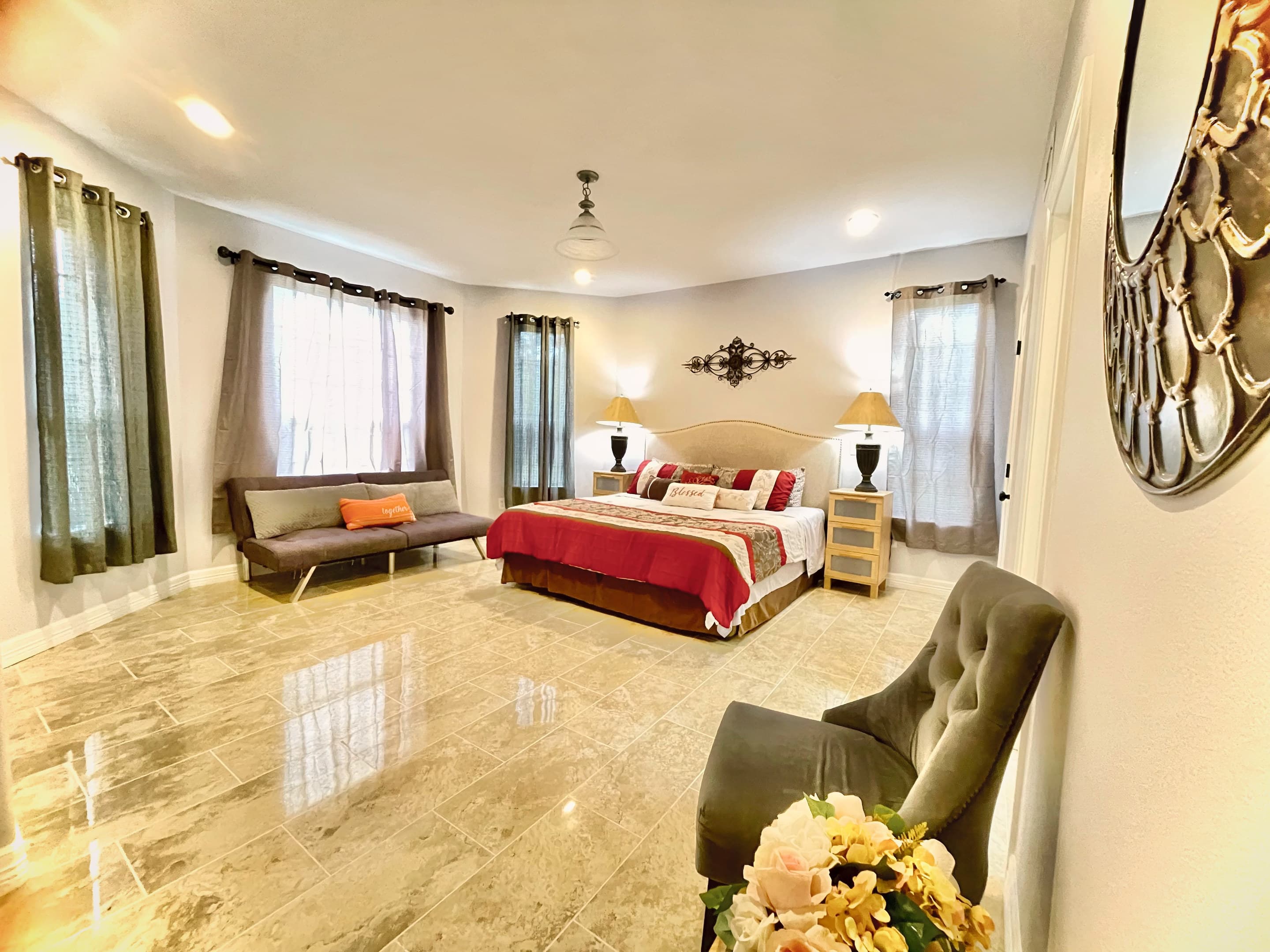 A guest suite with a king bed, a sitting area and polished stone-look floors