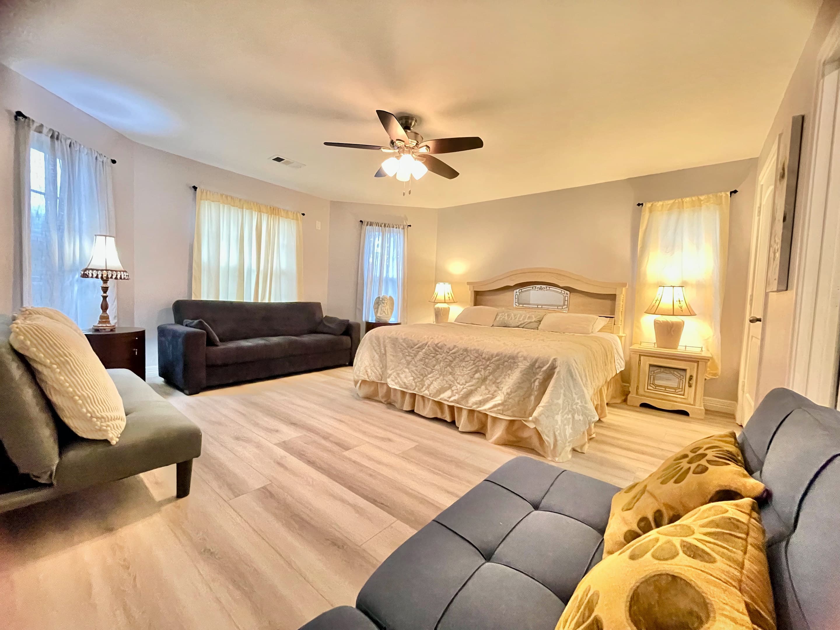 A suite with a king bed, a sofa and a sunlit reading corner