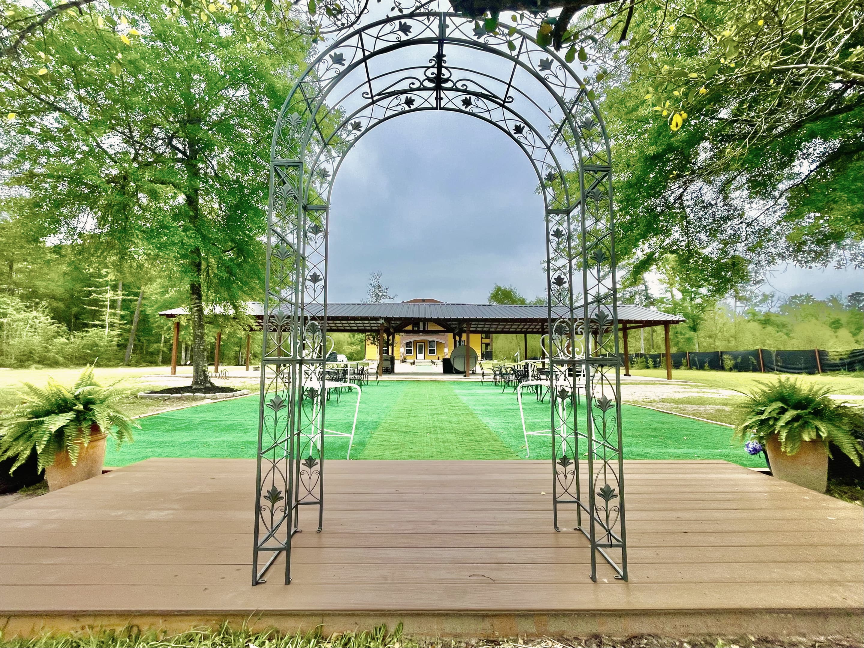 A wrought-iron arch on the timber stage at the edge of the turf patio