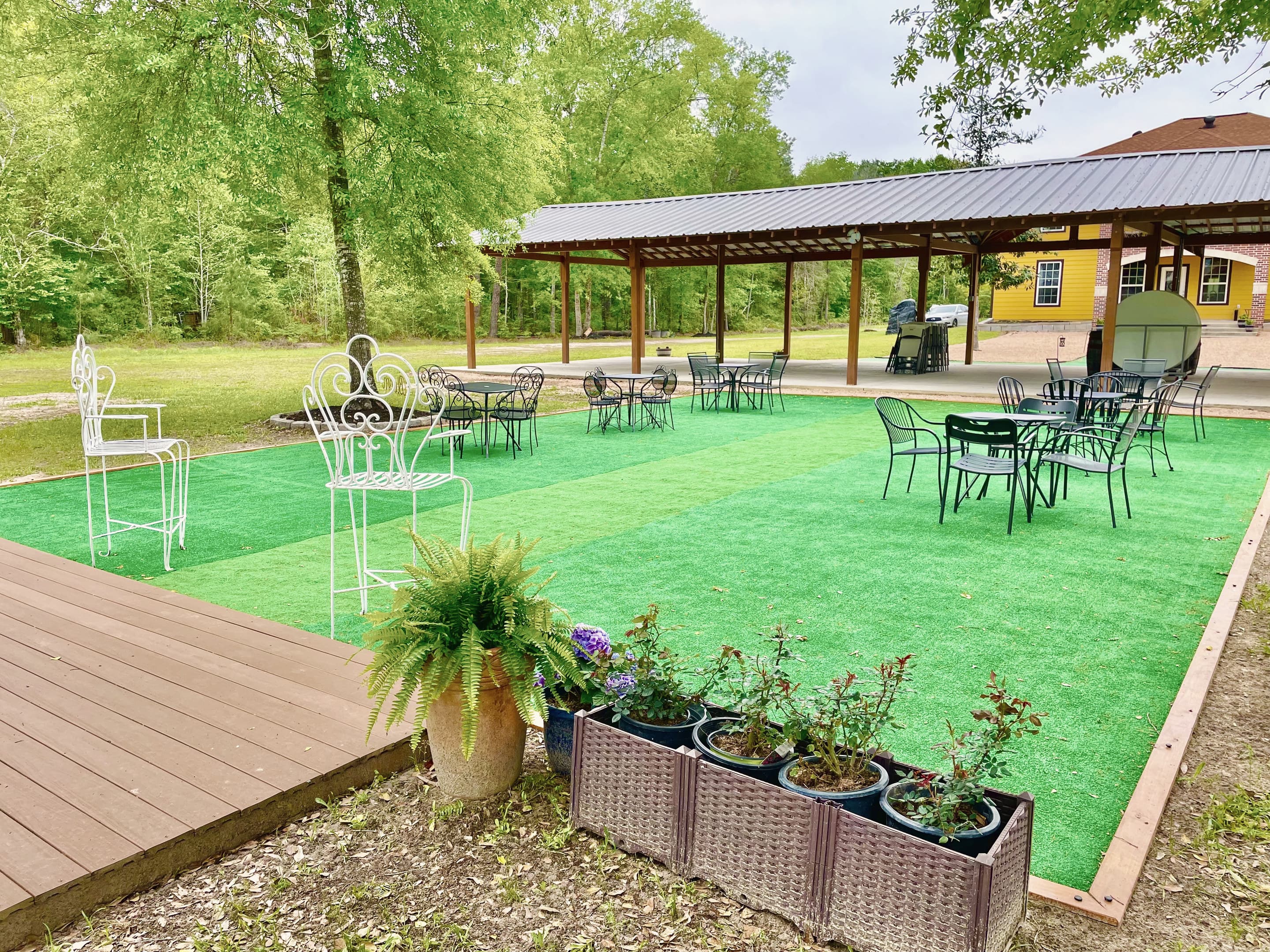 The turf patio with its timber stage deck and planters, the covered pavilion beyond